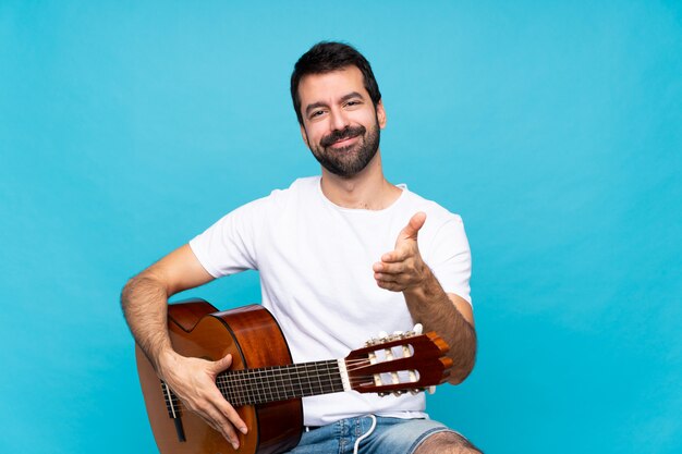 Zdjęcie młody człowiek z gitarą nad odosobnionymi błękitnymi trząść rękami dla zamykać dobrą ofertę