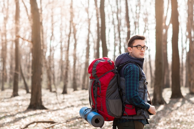Młody człowiek z plecakiem wycieczkuje w lesie