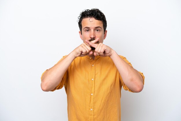 Młody człowiek z wąsami na białym tle, pokazując znak gestu ciszy