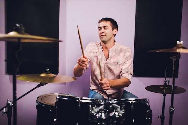 Młody człowiek za instalacją typu perkusyjnego w profesjonalnym studiu nagraniowym.