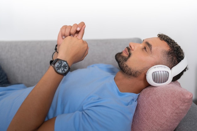 Młody człowiek zamyślony słuchanie muzyki odpoczywa na kanapie