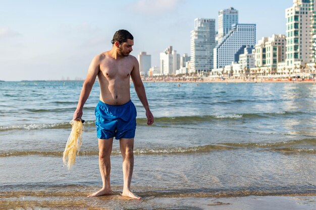 Młody człowiek zbiera śmieci na plaży