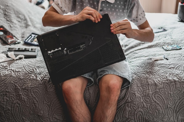 Młody człowiek zmienia pastę termiczną na laptopie
