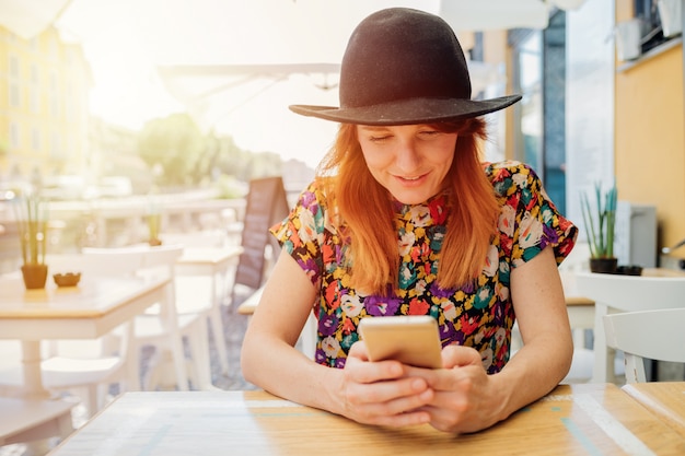 Młody dorosły kobiety obsiadania bar używa telefon