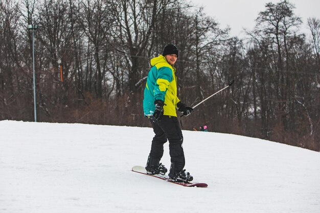 Zdjęcie młody dorosły mężczyzna snowboarding i robienie selfie na akcji kamery stylu życia