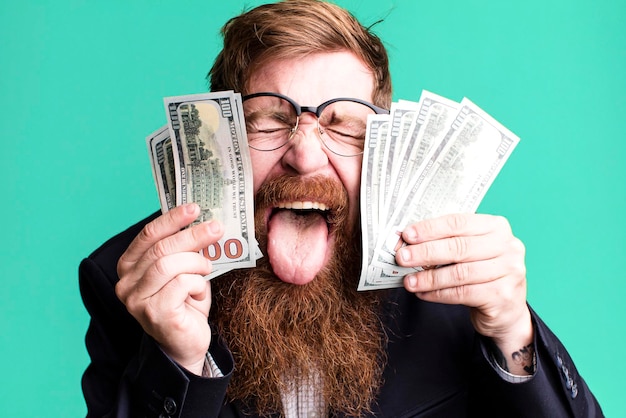 Zdjęcie młody dorosły rudy włos brodaty fajny biznesmen z banknotami dolara