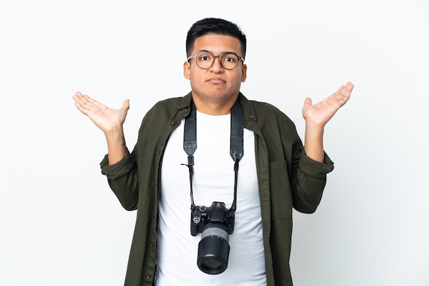Młody ekwadorski fotograf na białym tle mający wątpliwości podczas podnoszenia rąk