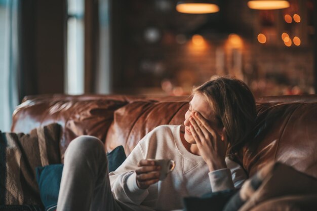 Zdjęcie młody, emocjonalny, wesoły nastolatek z długimi włosami, śmiechem i radością w przytulnym domu.