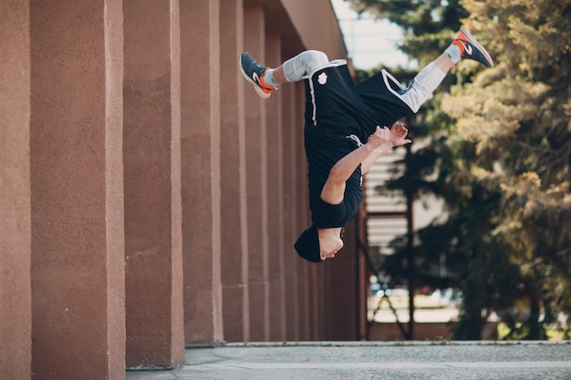 Młody facet sportowy robi parkour na ulicy miasta.