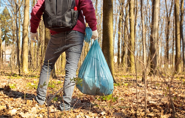 Młody facet trzyma dużą plastikową torbę z śmieci