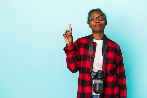 Młody fotograf african american kobieta na białym tle na niebieskim tle pokazując numer jeden z palcem.