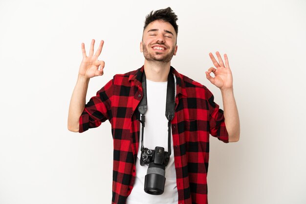 Młody fotograf kaukaski mężczyzna na białym tle w pozie zen