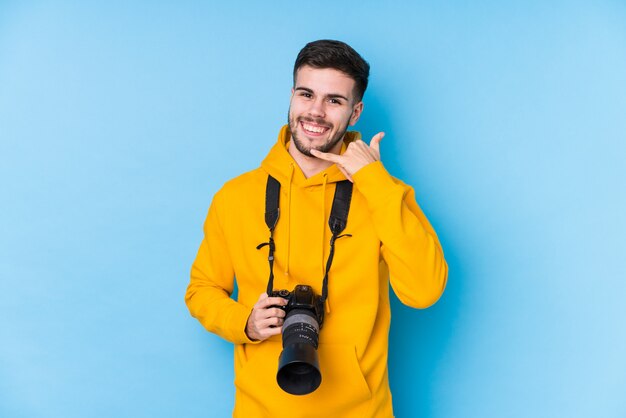 Młody fotografa mężczyzna pokazuje telefonu komórkowego wezwania gest z palcami