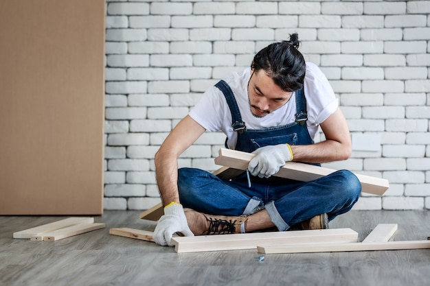 Młody hipster Azji człowiek pracujący jako złota rączka, montaż stół z drewna z wyposażeniem, koncepcja domu diy i samoobsługi w domu.