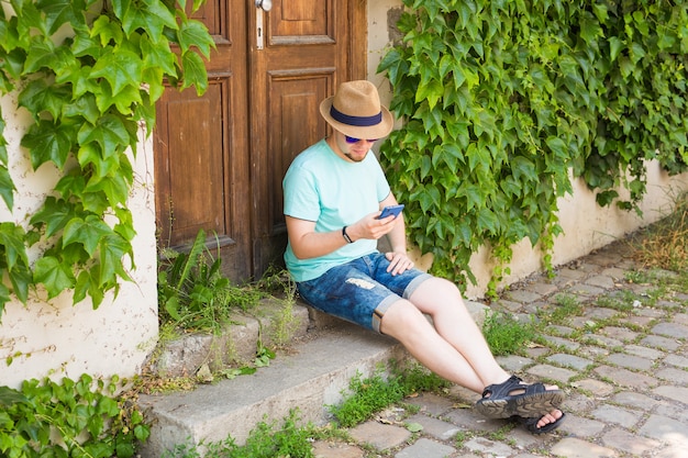 Młody hipster mężczyzna przy użyciu inteligentnego telefonu komórkowego na zewnątrz