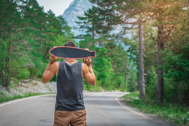 Młody hipster trzymający w dłoni fajny longboard