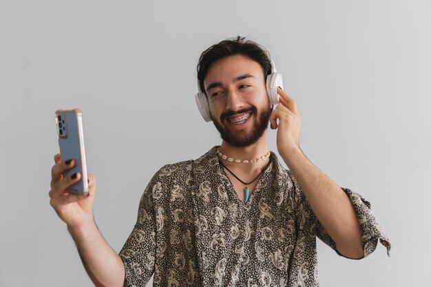Młody homoseksualny queer Latynos robi selfie z telefonem komórkowym podczas korzystania ze słuchawek