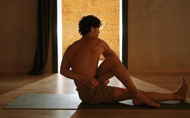 Zdjęcie młody i sportowy mężczyzna uprawia jogę i wykonuje asany