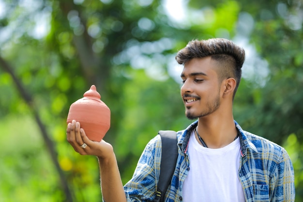 Młody Indianin College Boy Trzymając W Ręku Glinę Skarbonkę Na Tle Przyrody