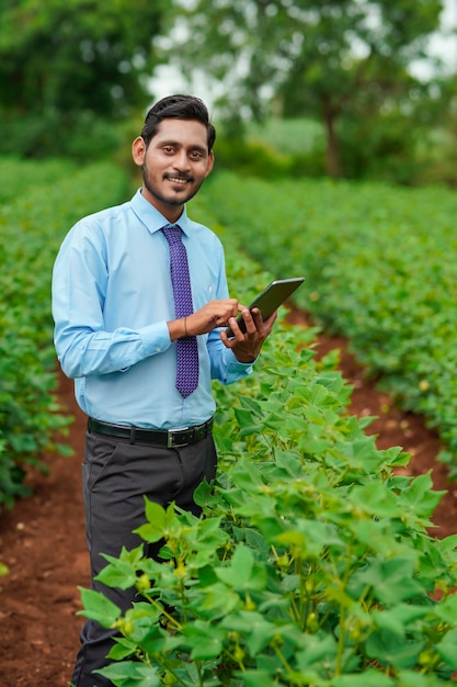 Młody indyjski agronom lub oficer za pomocą tabletu w dziedzinie rolnictwa.