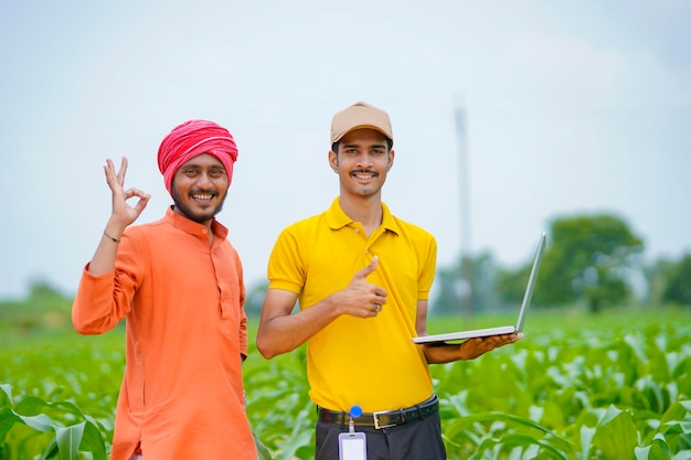 Młody indyjski bankier lub agronom pokazujący niektóre szczegóły rolnikom w laptopie na polu rolnictwa.