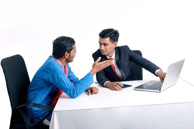 Młody Indyjski Bankier Udzielający Informacji Rolnikowi Na Laptopie W Biurze.