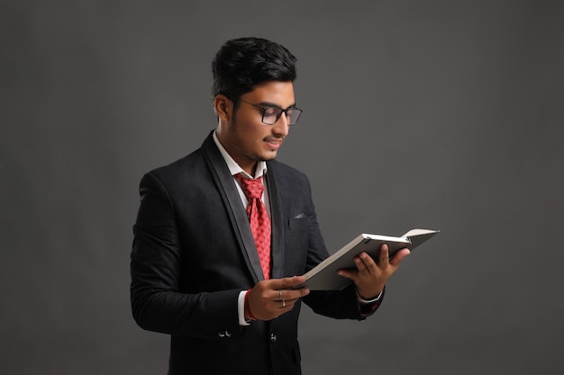 Zdjęcie młody indyjski człowiek sukcesu w biznesie lub wykonawczej w okularach i czytanie książki na ciemnym tle.