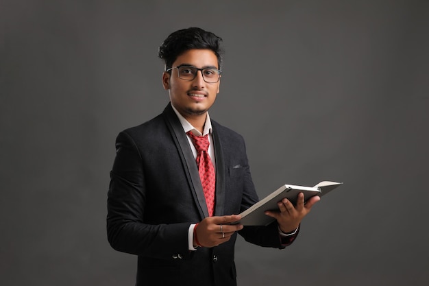 Zdjęcie młody indyjski człowiek sukcesu w biznesie lub wykonawczej w okularach i czytanie książki na ciemnym tle.