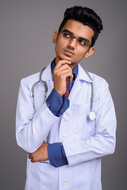 Młody indyjski lekarz mężczyzna przed szarej ścianie