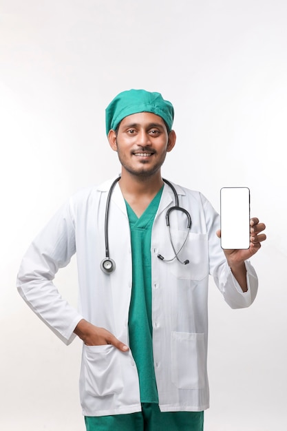 Młody indyjski lekarz pokazując ekran smartfona na białym tle.