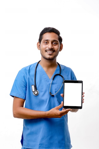 Młody indyjski lekarz pokazując ekran tabletu na białym tle.