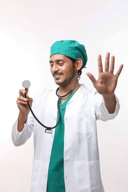 Młody indyjski mężczyzna Doktor trzyma w ręku stetoskop na białym tle.