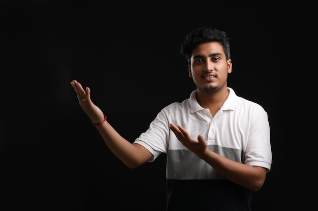 Młody indyjski mężczyzna pokazujący ekspresję na ciemnym tle