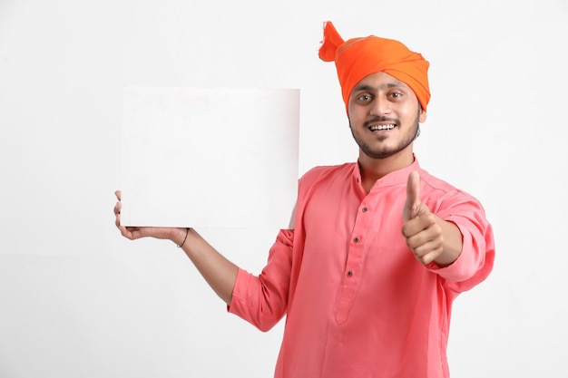 Młody indyjski mężczyzna trzyma białą tablicę na białej ścianie