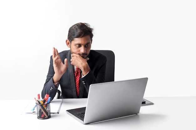 Młody indyjski mężczyzna w garniturze i pracujący na laptopie w biurze