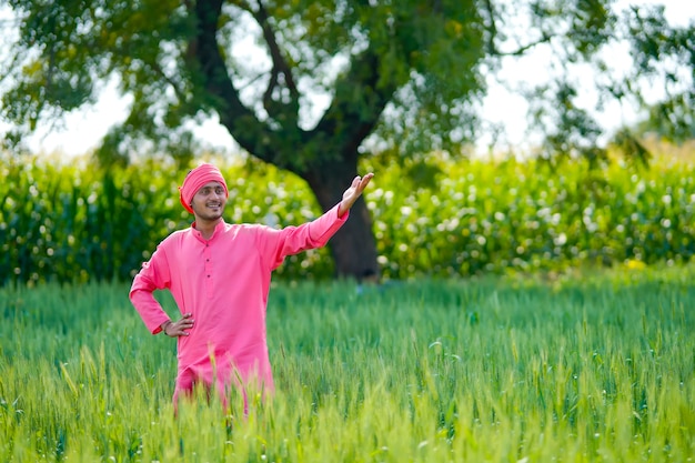 Młody indyjski rolnik stojący jego pole pszenicy i dając szczęśliwy wyraz