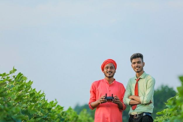 Młody Indyjski Rolnik Trzyma Pilota W Ręku I Kontroluje Latającego Drona Z Agronomem W Dziedzinie Rolnictwa
