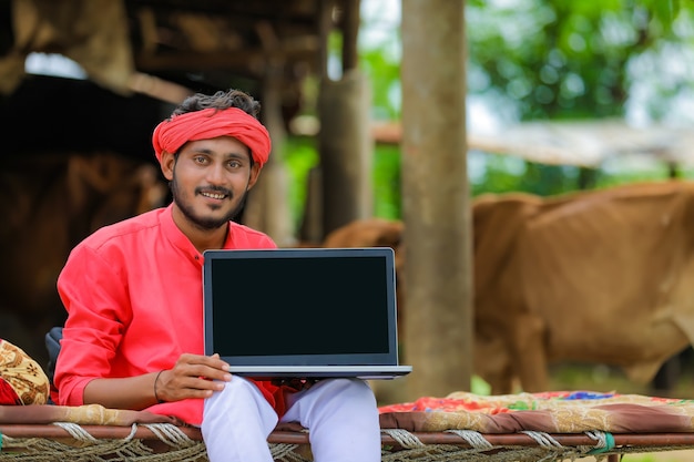 Młody indyjski rolnik za pomocą laptopa