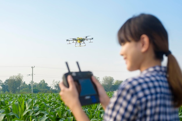 Młody inteligentny rolnik kontrolujący opryskiwanie dronem nawozów i pestycydów na polach uprawnych