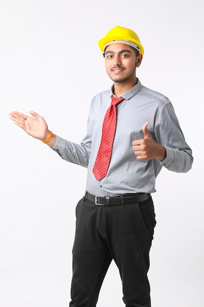 Młody inżynier indyjski nosi kask w kolorze żółtym i daje udany gest.