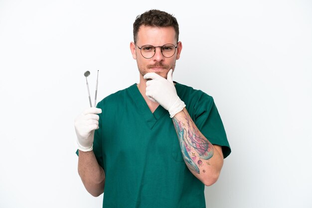 Młody kaukaski dentysta mężczyzna odizolowywający na białym tle myślący