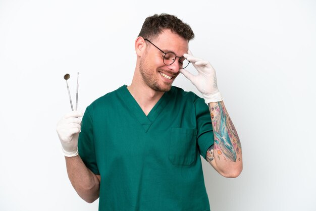 Młody kaukaski dentysta mężczyzna odizolowywający na białym tle śmieje się