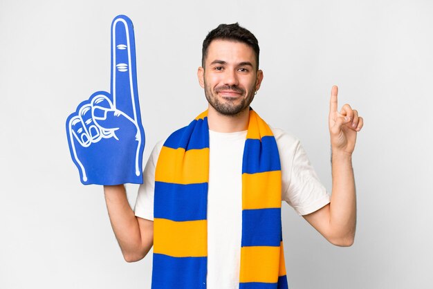 Młody kaukaski fan sportu mężczyzna na białym tle pokazujący i podnoszący palec na znak najlepszych