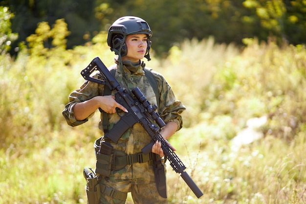 Młody kaukaski kobieta wojskowa trzyma w ręku pistolet w naturze, będzie polować, polowanie w lesie to hobby. gra z bronią