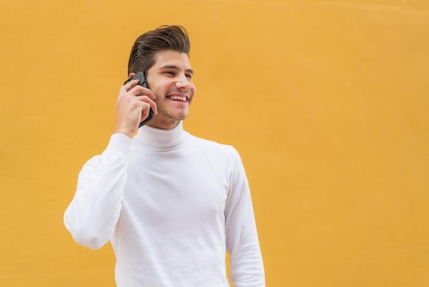 Młody kaukaski mężczyzna na zewnątrz prowadzi z kimś rozmowę przez telefon komórkowy