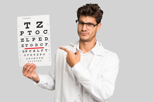 Młody kaukaski mężczyzna okulista trzyma na białym tle test optometrii