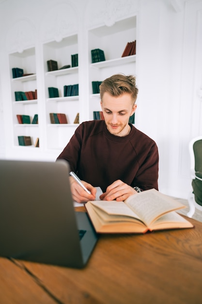 Młody kaukaski mężczyzna student studiuje z laptopem odlegle przygotowując się do egzaminu testowego