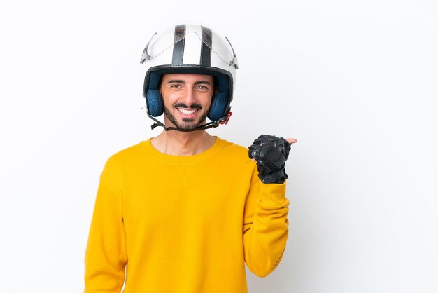 Młody kaukaski mężczyzna z kaskiem motocyklowym na białym tle wskazujący na bok, aby zaprezentować produkt