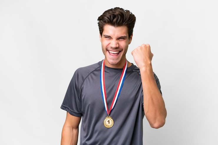 Zdjęcie młody kaukaski mężczyzna z medalami na białym tle świętuje zwycięstwo