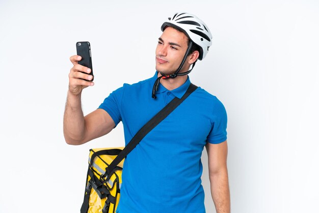 Młody kaukaski mężczyzna z plecakiem termicznym na białym tle robi selfie